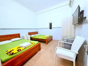 a bedroom with two beds and a tv and a chair at HAPPY TEA Motel in Long Hai