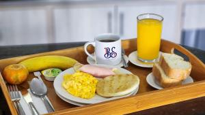 a tray with a breakfast tray with eggs eggs bacon and a drink at BE Suites Hotel Cali in Cali