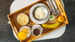 a tray of food with a bowl of soup and fruit at BE Suites Hotel Cali in Cali +37 photos