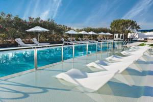 a row of white lounge chairs and a swimming pool at Elba Premium Suites - Adults Only in Playa Blanca