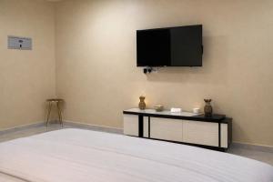 a bedroom with a bed and a flat screen tv on the wall at Alsharafh room 2 in Al ‘Aqar