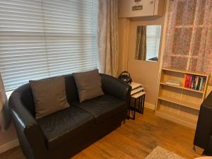 a black leather couch in a living room with a window at 7 The Diamond in Ballycastle