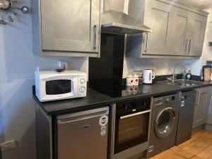 a small kitchen with a microwave and a sink at 7 The Diamond in Ballycastle