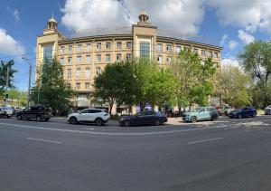 a large building with cars parked in front of it at Zolotoi Drakon Hotel in Almaty