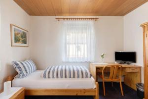 a bedroom with a bed and a desk with a computer at Hotel Garni Siedlerstube 2 in Nürtingen