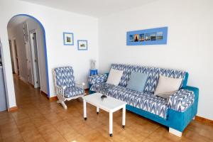 a living room with a blue couch and two chairs at SOL NAIXENT in Fornells +24 photos