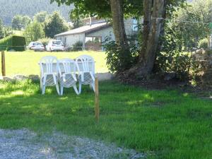 two white chairs sitting in the grass near a tree at Airellier du Pilat in Marlhes +3 photos
