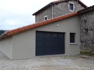 a garage with a black garage door on a building at Airellier du Pilat in Marlhes