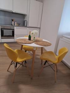 a kitchen with a table and two yellow chairs at Apartman MWM Brno in Brno