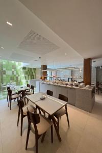 a dining room with tables and chairs and a kitchen at Hotel Acalanto Feira de Santana in Feira de Santana