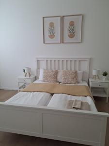 a white bedroom with a large white bed with two tables at Apartman MWM Brno in Brno