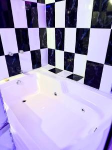 a white bath tub with a black and white checkered wall at Hotel Sol y Luna 1 in Medellín
