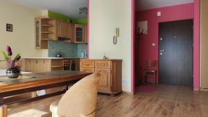 a kitchen with a wooden table and pink walls at Apartament Ziołowy in Augustów