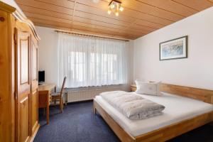 a bedroom with a bed and a desk and a window at Hotel Garni Siedlerstube 2 in Nürtingen