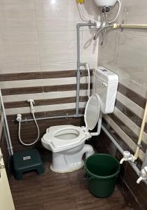 a bathroom with a toilet and a green bucket at Rudraksh Homestay in Dwarka +17 photos