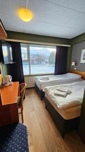 a room with two beds and a desk and a window at Hótel Austur in Reyðarfjörður