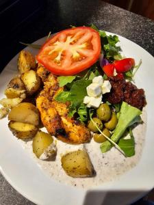 a plate of food with a salad and a tomato at Hótel Austur in Reyðarfjörður +78 photos