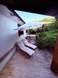a patio with two chairs and an umbrella at Casetta La Pera in Perarolo +25 photos