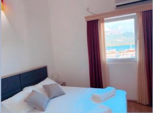 a bedroom with a bed with two pillows and a window at Apart hotel Samardzic in Tivat