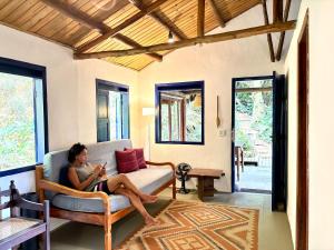 a woman sitting on a couch in a living room at Casa Botanique Jungle Retreat in Abraão