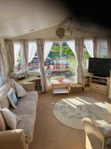 a living room with a couch and a flat screen tv at Cosy caravan Sunbeach in Llwyngwril