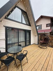 a patio with a table and chairs on a wooden deck at A-frame У Евелінки in Vorokhta