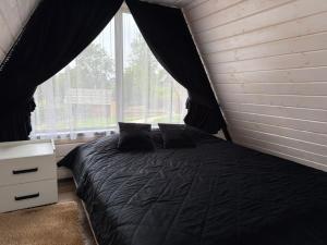 a bedroom with a black bed and a window at A-frame У Евелінки in Vorokhta