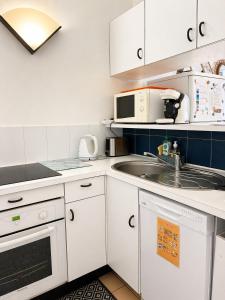 a small kitchen with white cabinets and a sink at Studio cabine pied dans l eau climatisé, parking et wifi haut débit in Canet-en-Roussillon