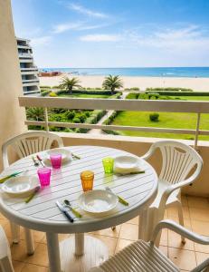 a white table and chairs on a balcony with a view of the beach at Studio cabine pied dans l eau climatisé, parking et wifi haut débit in Canet-en-Roussillon