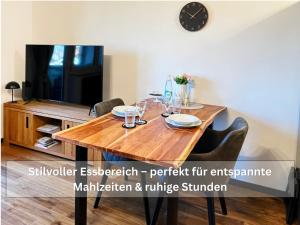 a dining room table with chairs and a clock on the wall at Ruhige Ferienwohnung Seemöwe mit Balkon - ideal für Paare & Radurlauber in Radolfzell am Bodensee