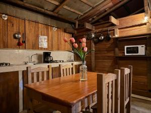 a kitchen with a wooden table with a vase of flowers on it at Straw hat suites La punta in Santa María Colotepec