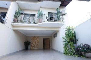 a white building with two balconies and potted plants at Pousada House Garden in Goiânia