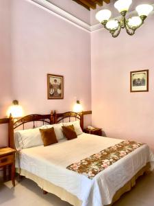 a bedroom with a large white bed with a chandelier at Casa del Agua in Guanajuato
