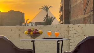 a table with a bowl of fruit and two glasses of orange juice at Casa Pyramids View in Cairo