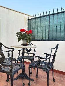 two chairs and a table with a vase with red flowers at DomusVenere in Santa Croce Camerina