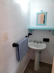 a white bathroom with a sink and a mirror at La Vecindad del Sol Depto G in Miramar +12 photos