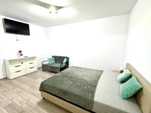 a white bedroom with a bed and a chair at David Apart in Otopeni