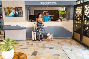 a woman standing with a dog in a lobby at Hotel Valladolid in Santa Marta