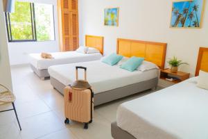 a hotel room with two beds and a suitcase at Hotel Valladolid in Santa Marta +62 photos
