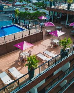 a balcony with tables and umbrellas and a pool at MK Flat - A 2 quadras do mar in Matinhos