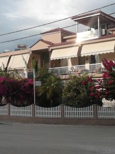 a white fence in front of a house with flowers at ILIANA apartments in Preveza