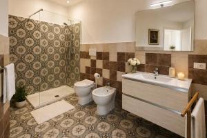 a bathroom with a toilet and a sink and a tub at Immacolata Rooms in Noto