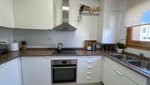 a kitchen with white cabinets and a sink at Casa de playa in Roda de Bará