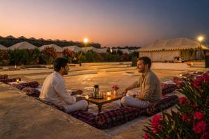 two men sitting around a coffee table at sunset at Sky Desert Safari Jaisalmer & Spa in Jaisalmer