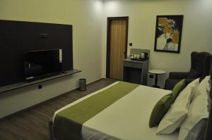 a hotel room with a bed and a flat screen tv at The Royal Palace Inn in Almora