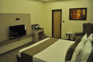 a hotel room with a bed and a flat screen tv at The Royal Palace Inn in Almora