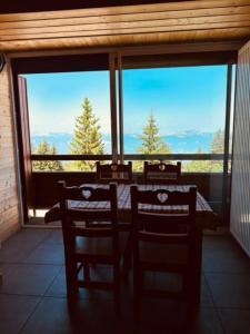 a room with a table and chairs and a large window at « Le doux Chalet » Roche Béranger in Chamrousse