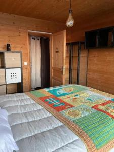 a bedroom with a large bed with a quilt on it at « Le doux Chalet » Roche Béranger in Chamrousse