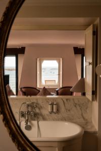 a mirror reflecting a bathroom with a sink and a window at Manoir de Lan Kerellec - Relais & Châteaux - Etoilé Michelin in Trébeurden