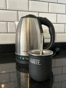 a coffee pot and a cup with a spoon in it at Depto Monroe 2 in Buenos Aires